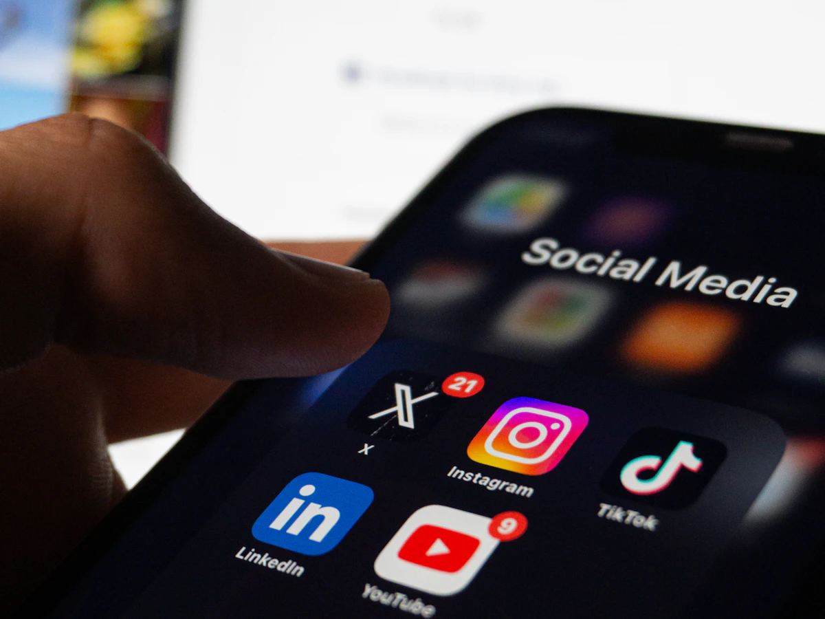 Pessoa segurando um celular com aplicativos de redes sociais abertos na tela